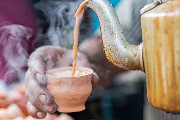 Chai tea being poured into a clay chai cup